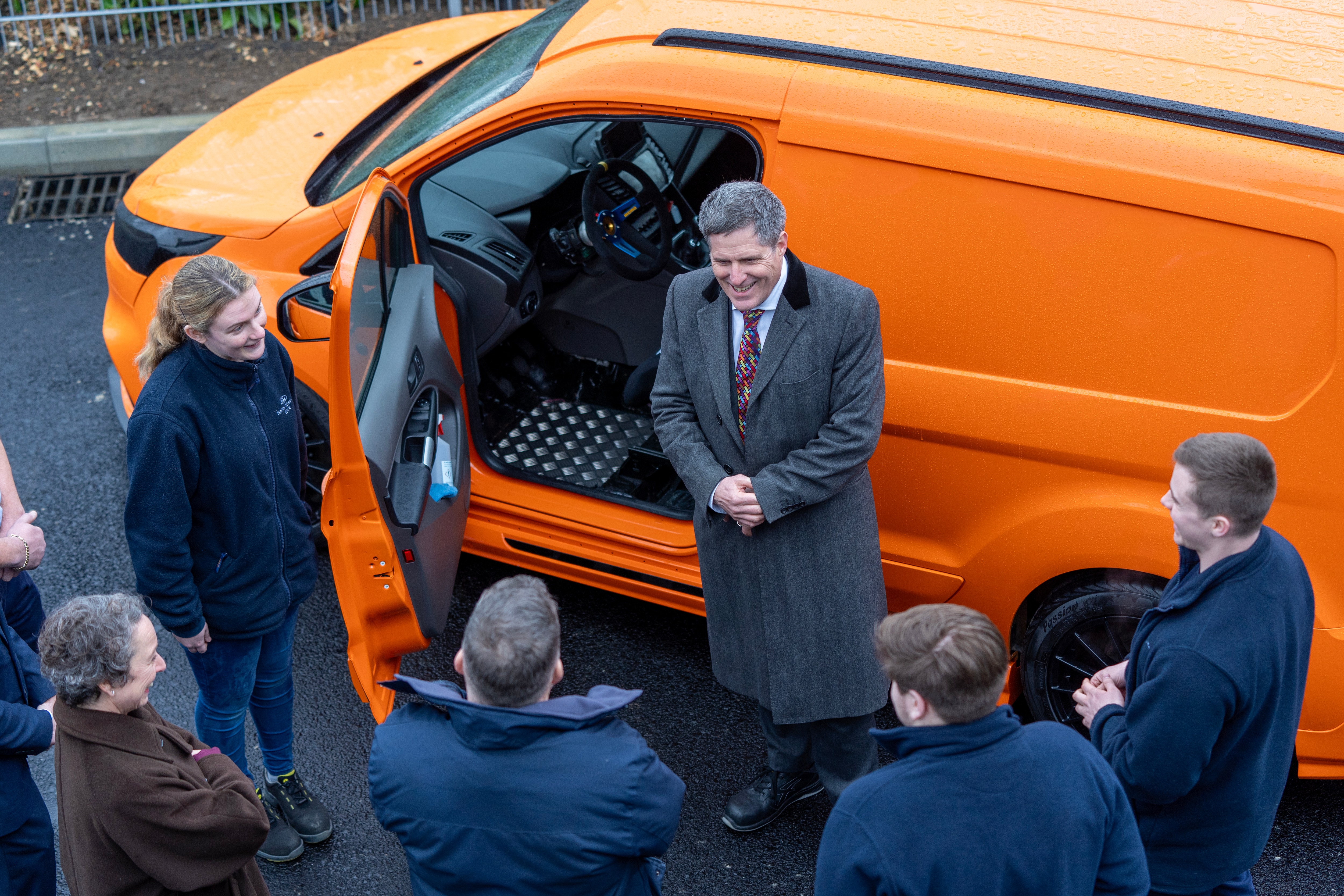 A man talking outside an orange van to a crowd